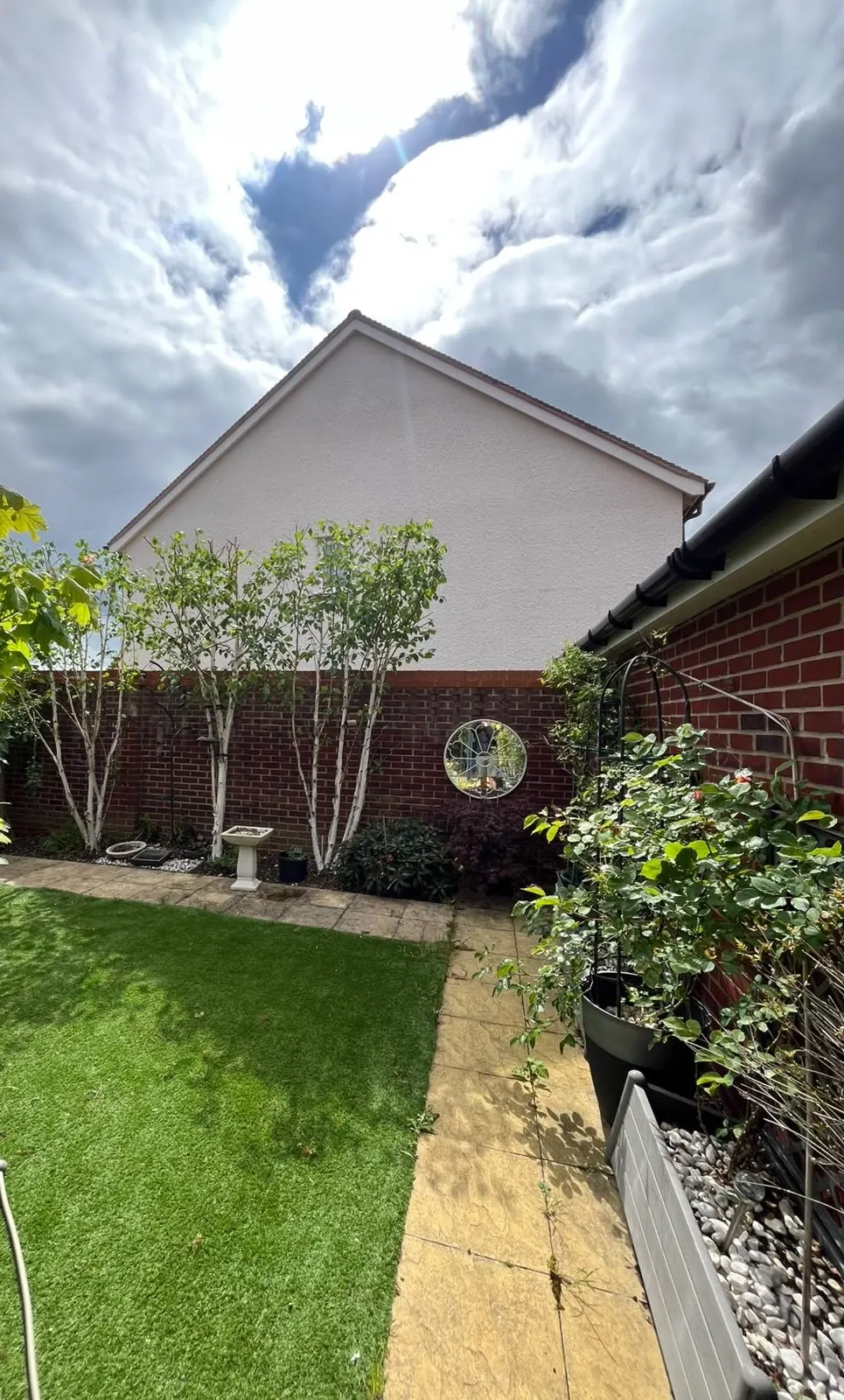 The same garden trees beside the wall and white gable after their crowns were cut back